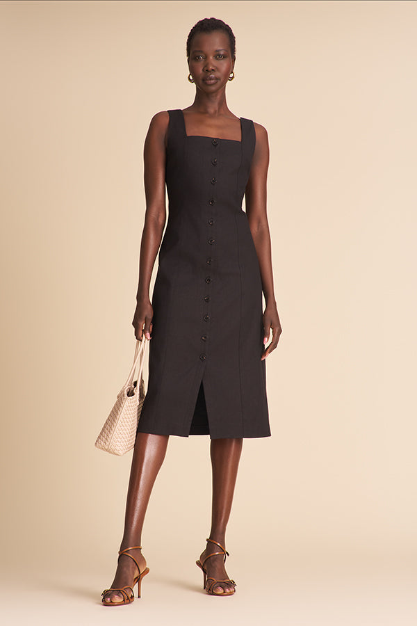 Woman wearing a black linen dress with black buttons on a beige background | Exclude | Grid