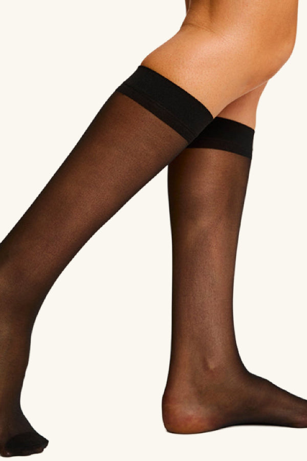 Black sheer stockings worn by a person on a white background