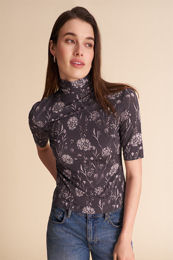 Woman wearing a patterned top and jeans on a beige background | Exclude | Grid