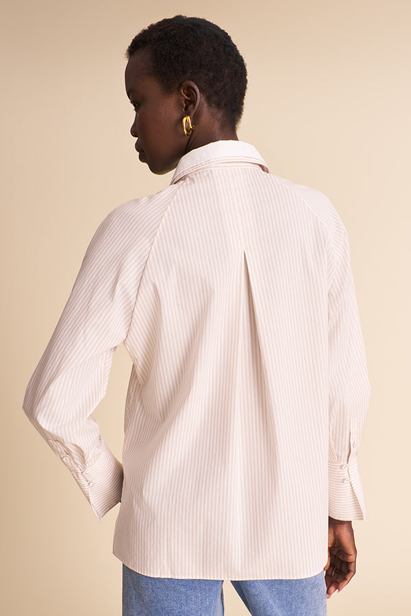 A model shown from the back wearing a cream-colored, vertically striped button-down shirt and light blue jeans against a solid beige background. | Exclude