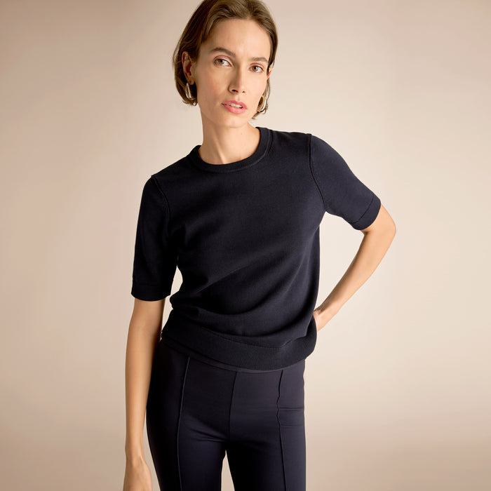 Woman wearing a black outfit against a beige background | Lead