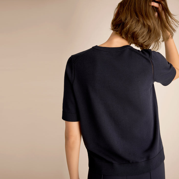 Person wearing a navy blue top with a plain background