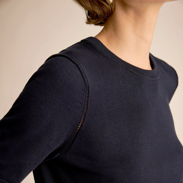 Navy blue sweater worn by a person on a beige background