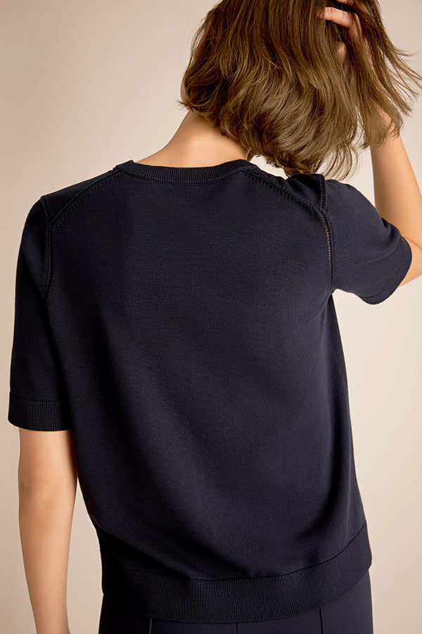 Person wearing a navy blue top with a neutral background | Exclude