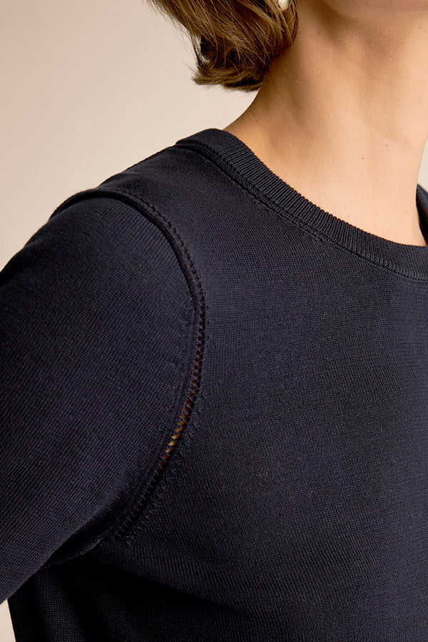 Navy blue sweater worn by a person, focusing on the shoulder and neckline area. | Exclude | Grid Hover