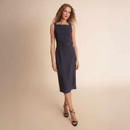 Woman wearing a navy dress with a belt on a beige background | Lead