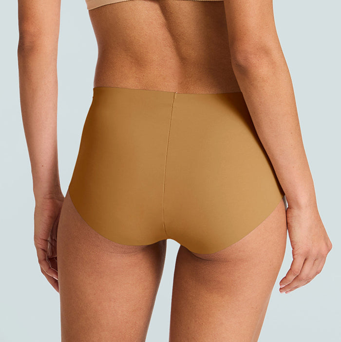 Person wearing a beige sports bra and high-waisted mustard yellow underwear on a light blue background