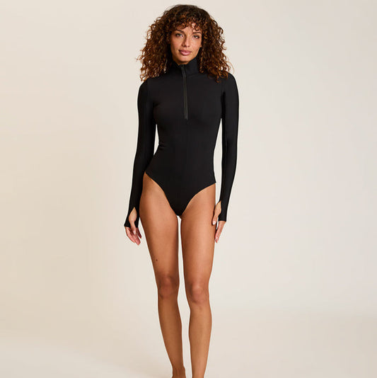 Woman wearing a black long-sleeve bodysuit on a beige background | Lead