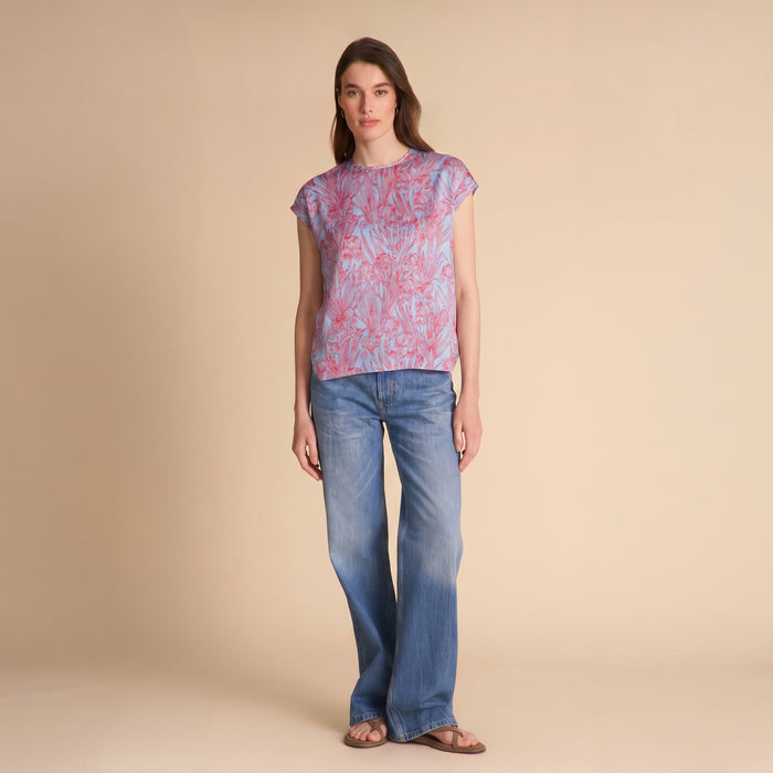 Woman wearing a patterned top and jeans on a beige background