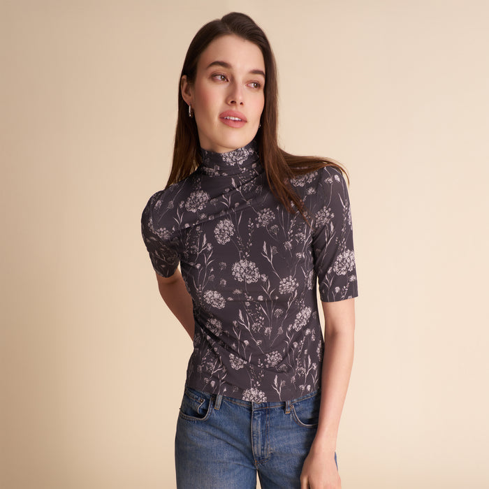 Woman wearing a patterned top and jeans on a beige background | Lead