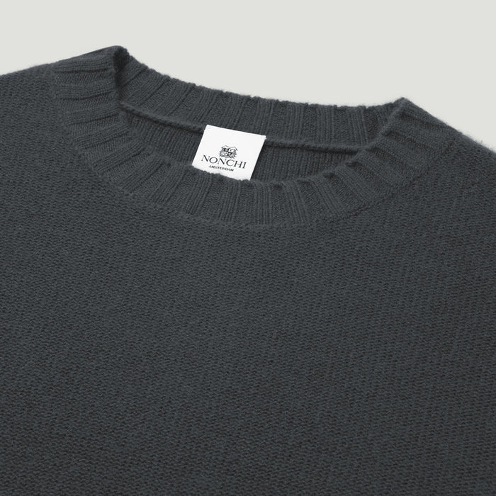 Dark gray sweater with a brand label on a light gray background