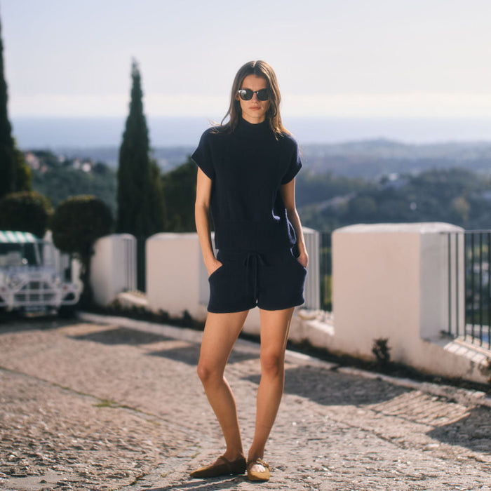 Woman in a black outfit standing on a stone path with a scenic background