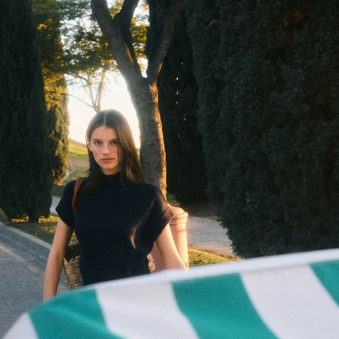 Woman walking on a path with trees and a road in the background