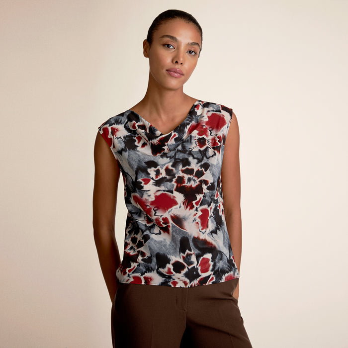 Woman wearing a sleeveless top with a colorful abstract pattern on a beige background