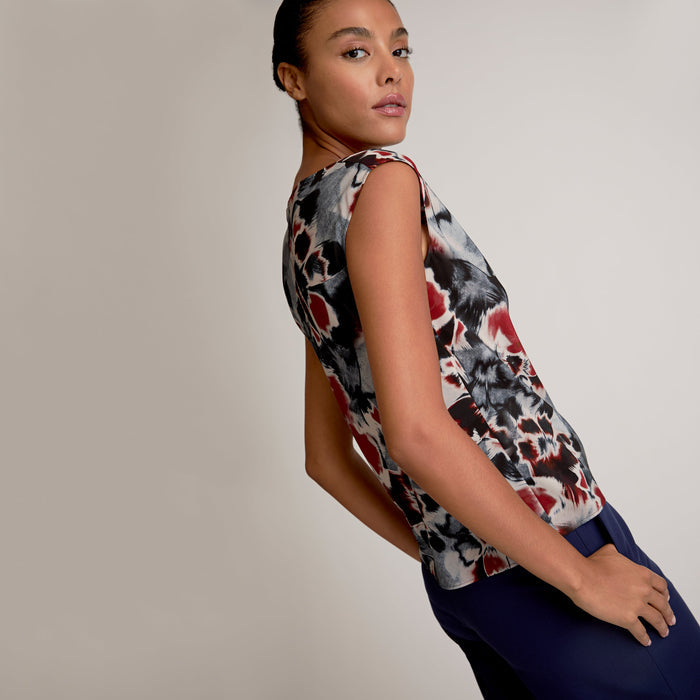 Woman wearing a sleeveless top with a colorful abstract pattern on a plain background | Exclude