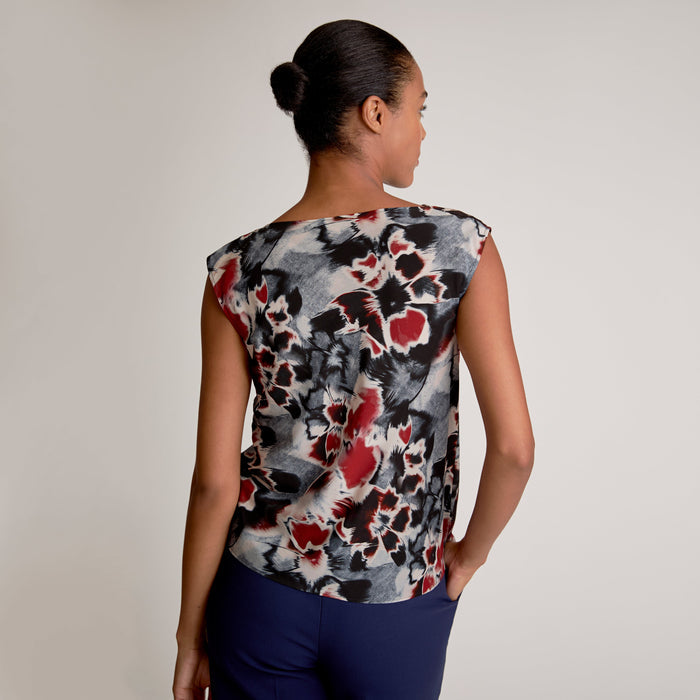 Woman wearing a sleeveless top with a floral pattern on a plain background | Exclude