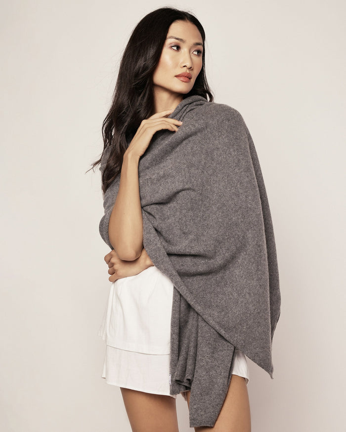 Woman wearing a gray shawl over a white top against a plain background