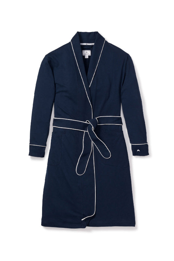 Woman wearing navy pajama set with white piping on a beige background | Grid | Exclude