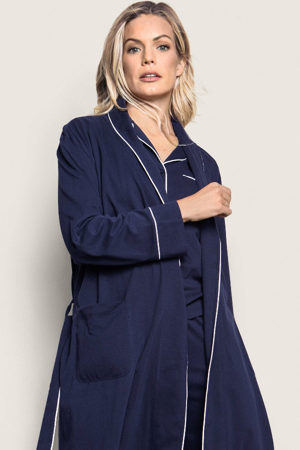 Woman wearing a navy blue robe with white piping on a beige background | Grid Hover | Exclude