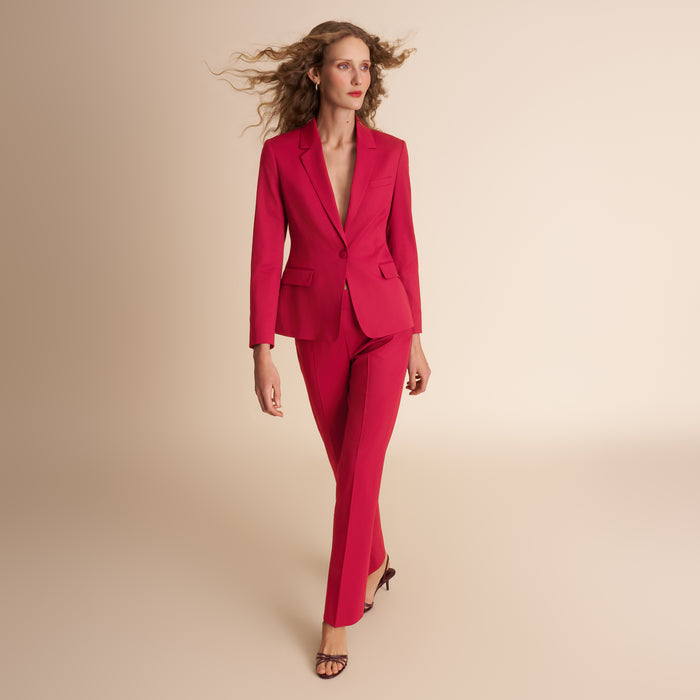 Woman wearing a red suit against a beige background