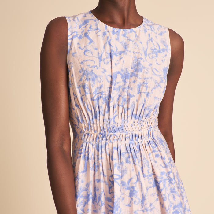 Woman wearing a sleeveless dress with blue and beige abstract pattern on a beige background